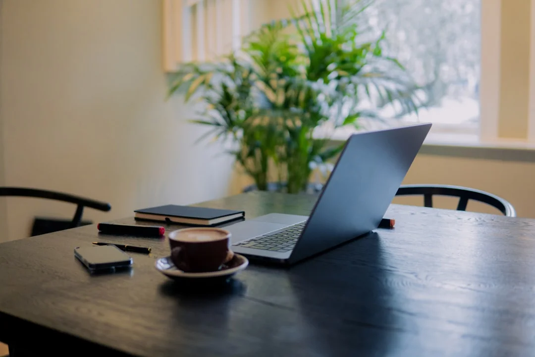 Close-up of hands typing on a laptop at an office desk, suggesting work or online communication.